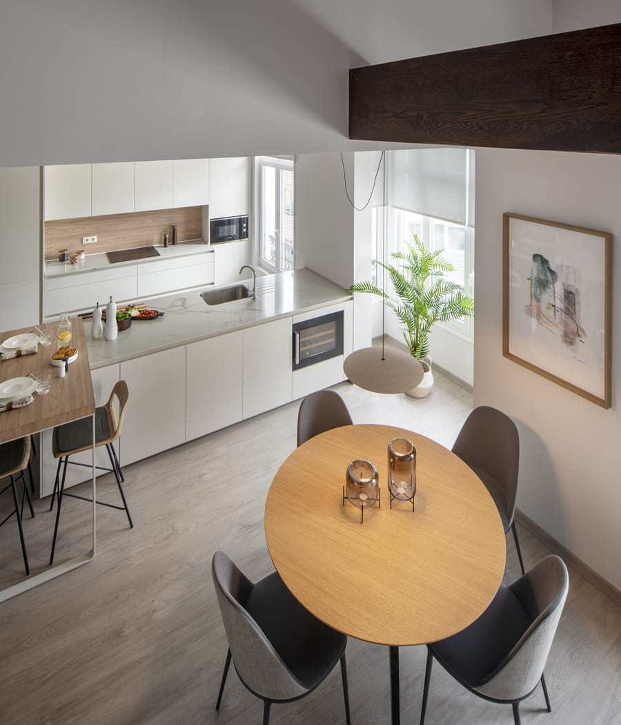 White, open-plan kitchen with island and centre table