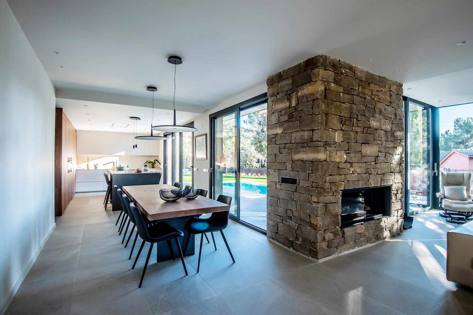 White, stone and wood kitchen that opens out to the dining room and living room