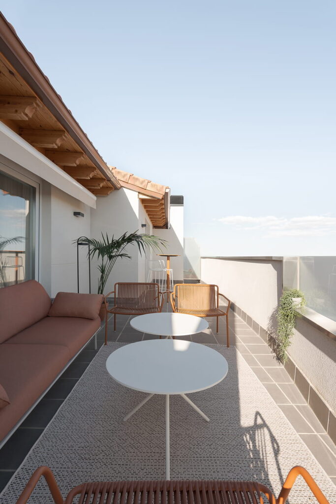 Amplia terraza con sofá y mesas de exterior.