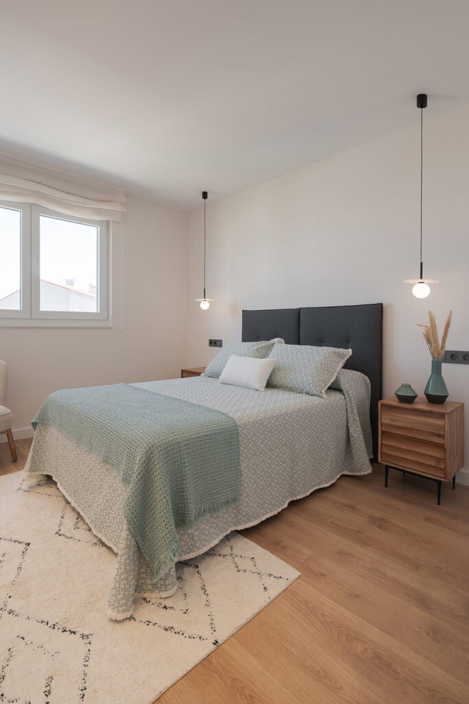 Minimalistische slaapkamer met hangende verlichting en houten vloeren.