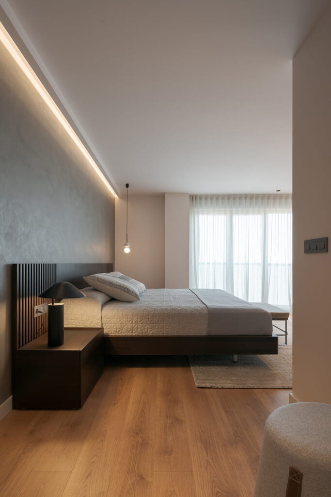 Dormitorio minimalista, suelos de madera y paredes grises.