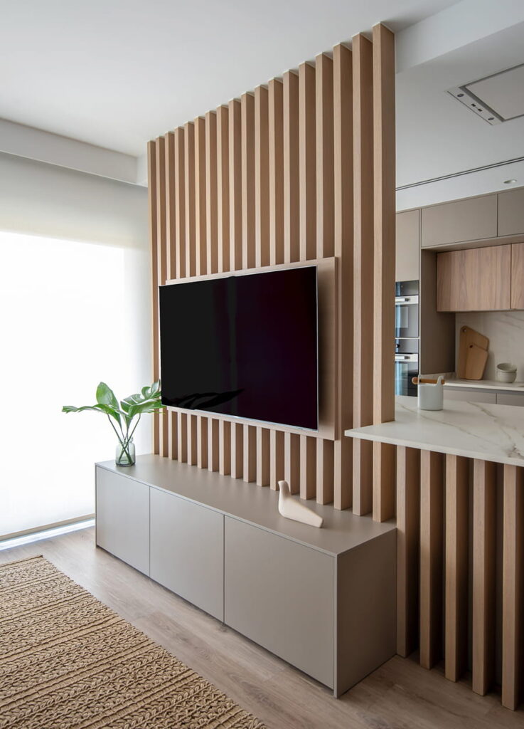 Light elm slats integrated into kitchen island with flat television.