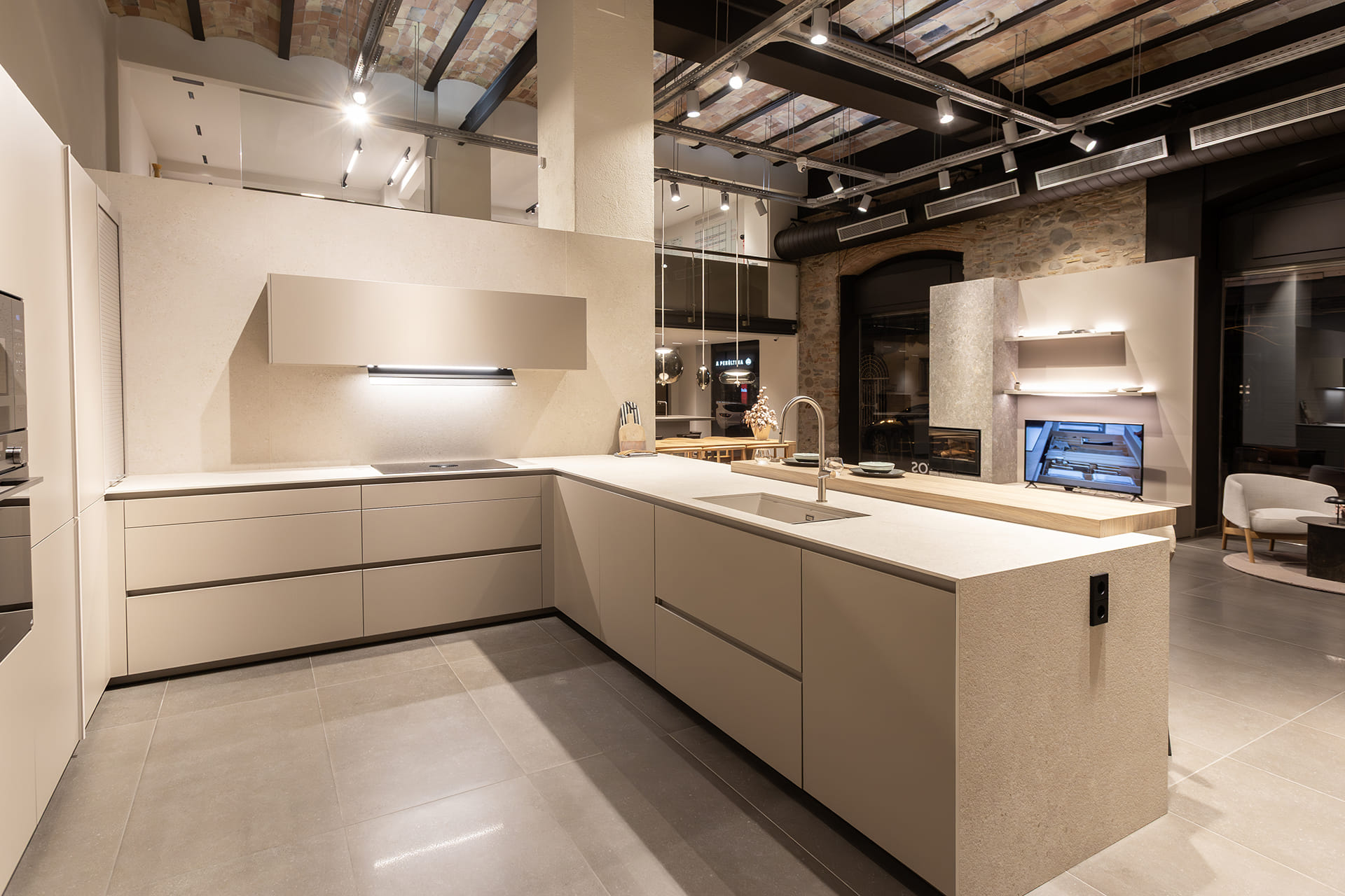 Sand Grey kitchen with counter and stools at the Santos kitchens showroom in Girona.