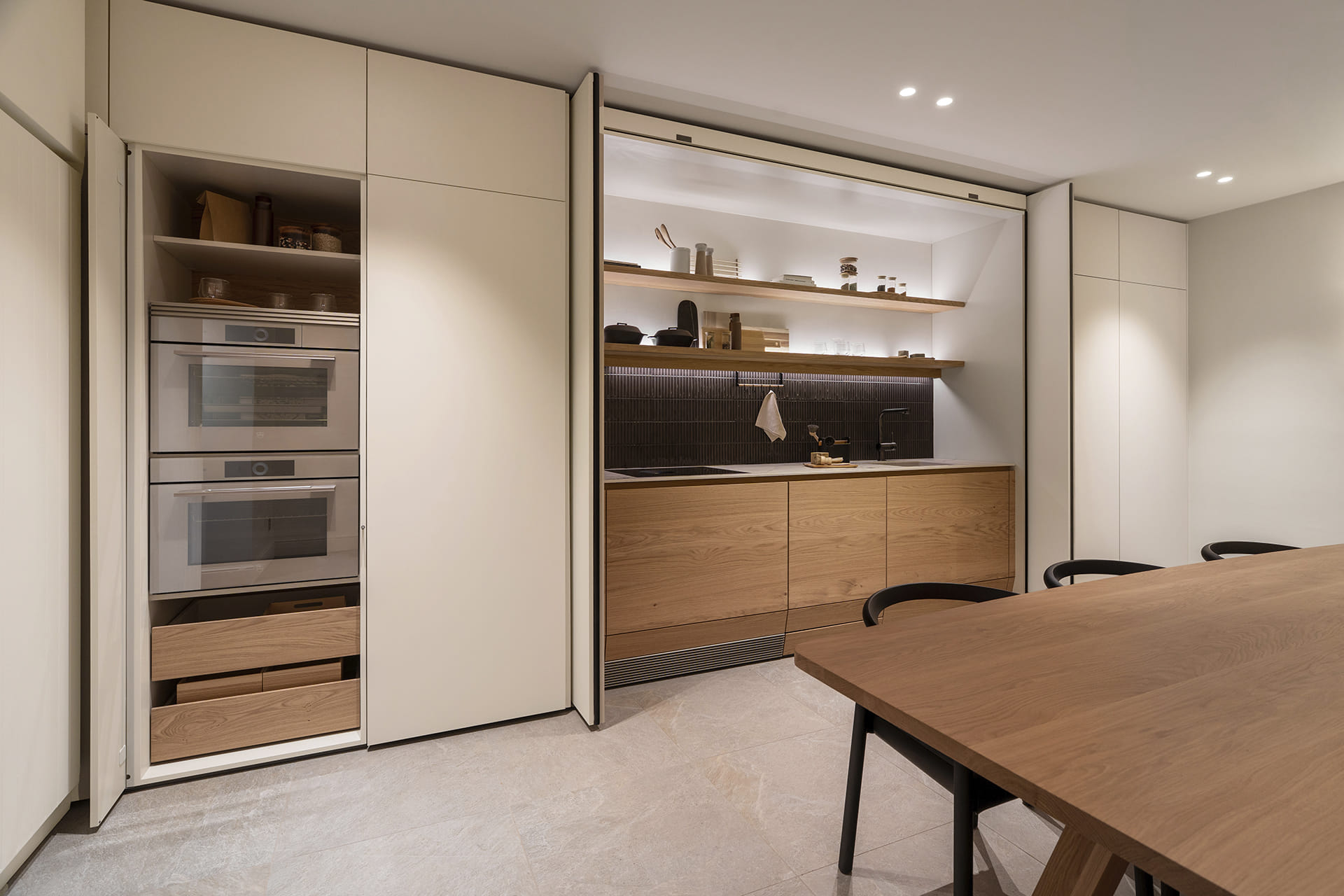 Single-wall kitchen concealed behind pocket doors with integrated appliances at the Santos Kitchens showroom in Switzerland.