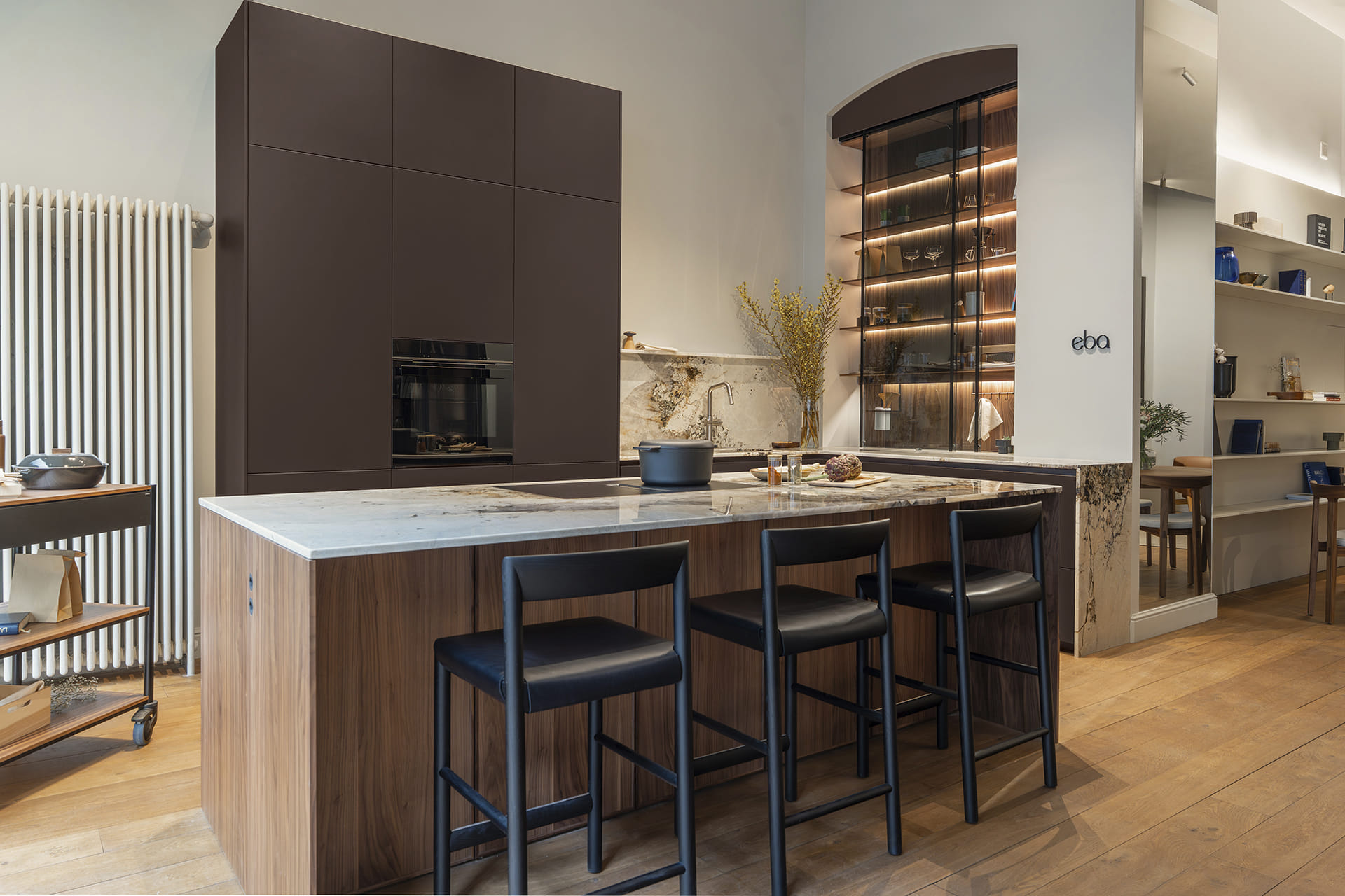 View of the dark brown kitchen with island at the exclusive showroom eba Genève.