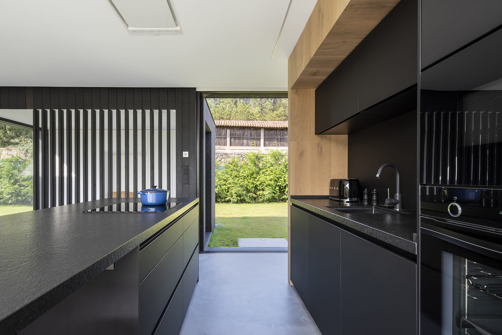 Black and wood kitchen open to the outside by Santos Kitchens.