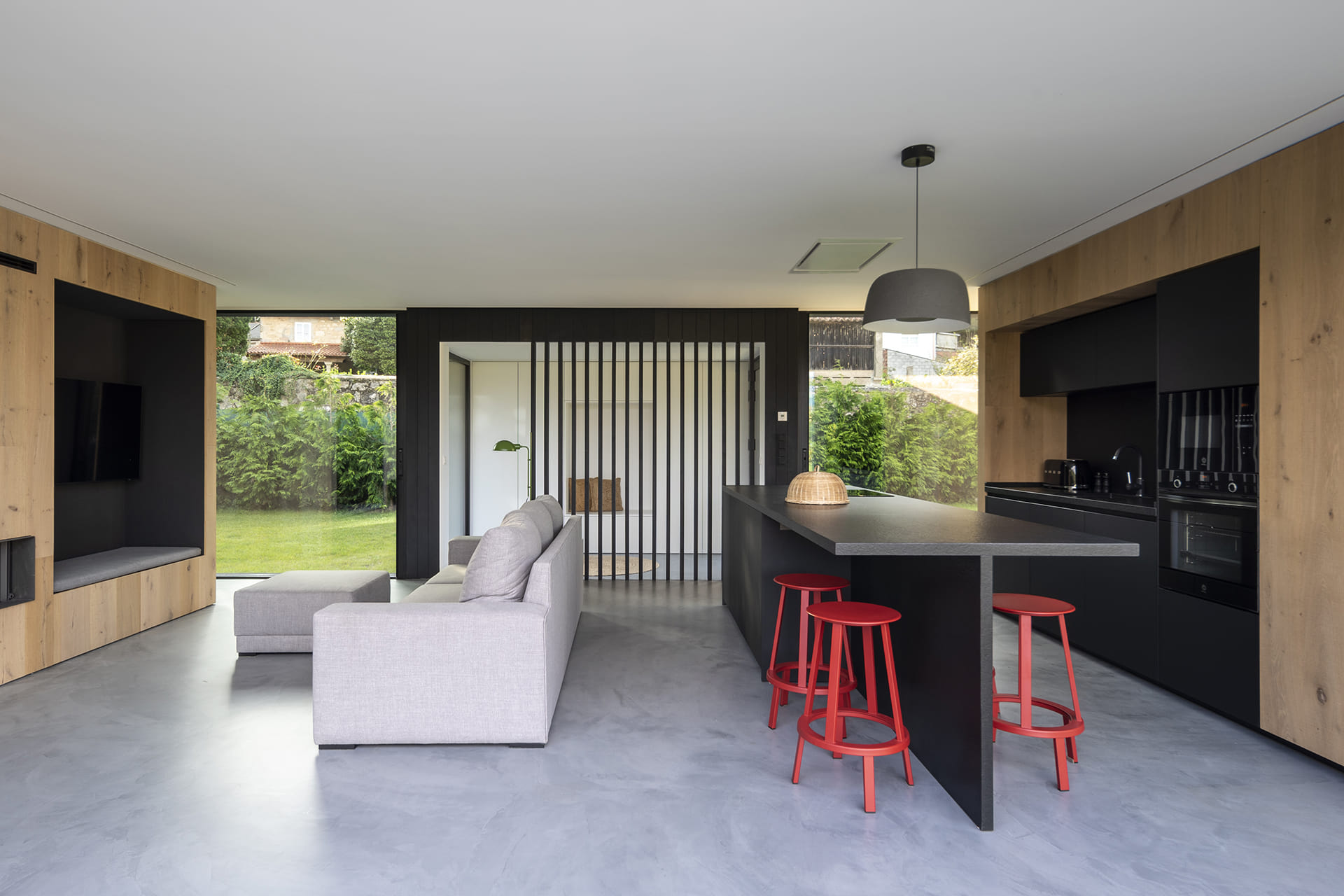 Black and wood kitchen open to the lounge with centre island and stools.