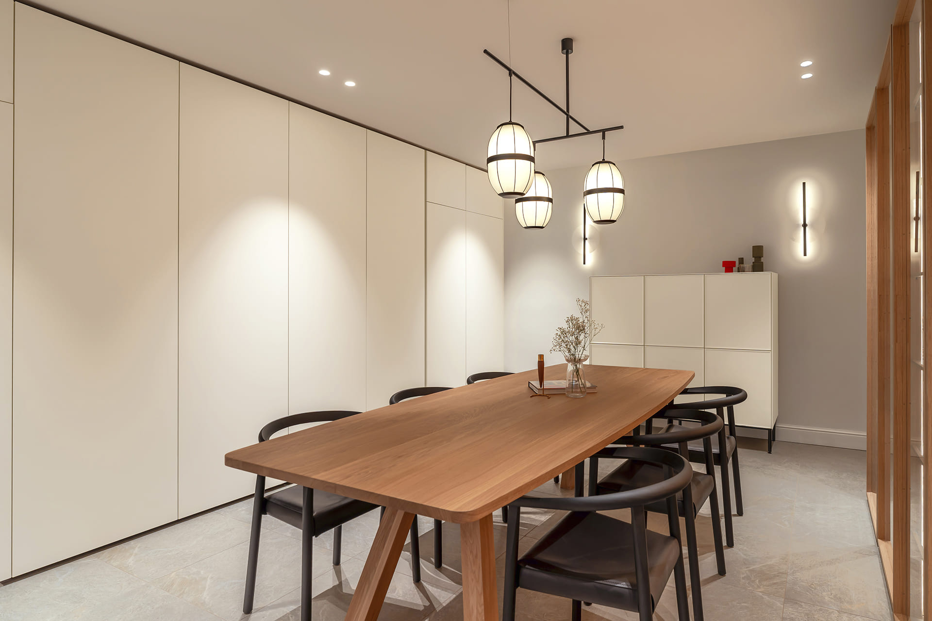 Dining area with white retractable units at the Santos Kitchens showroom in Switzerland.