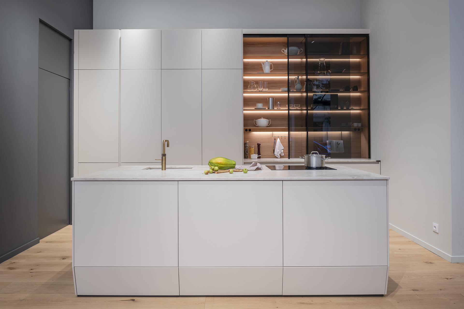 Cocina beige con isla y vitrinas iluminadas en el showroom de Santos en Zaragoza.