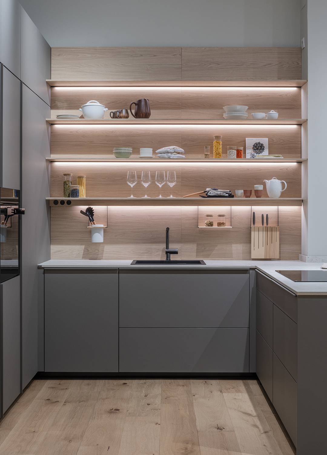 Cocina gris y madera con estantes iluminados en showroom de Santos.