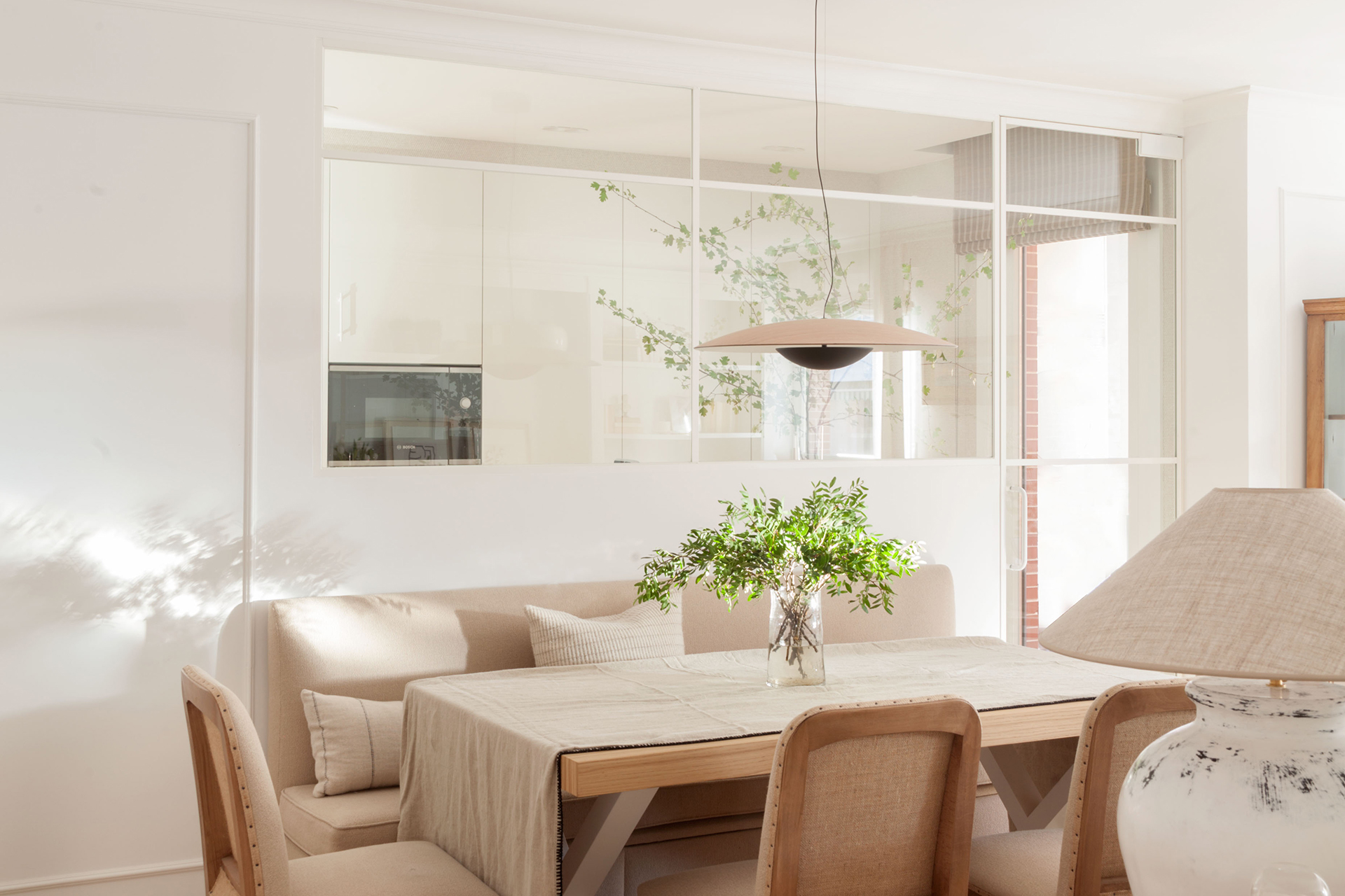 Cocina blanca abierta al comedor con cerramiento acristalado de Santos.