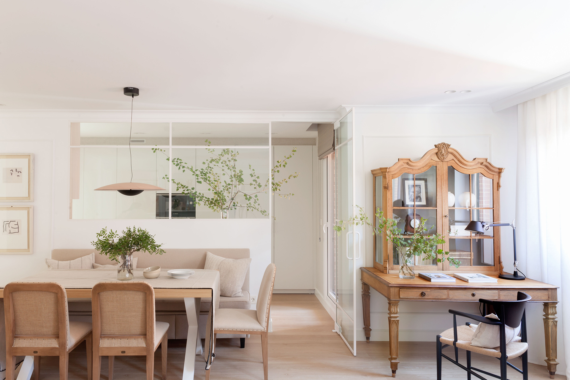 Cocina blanca abierta al salón con cerramiento de cristal de Santos.