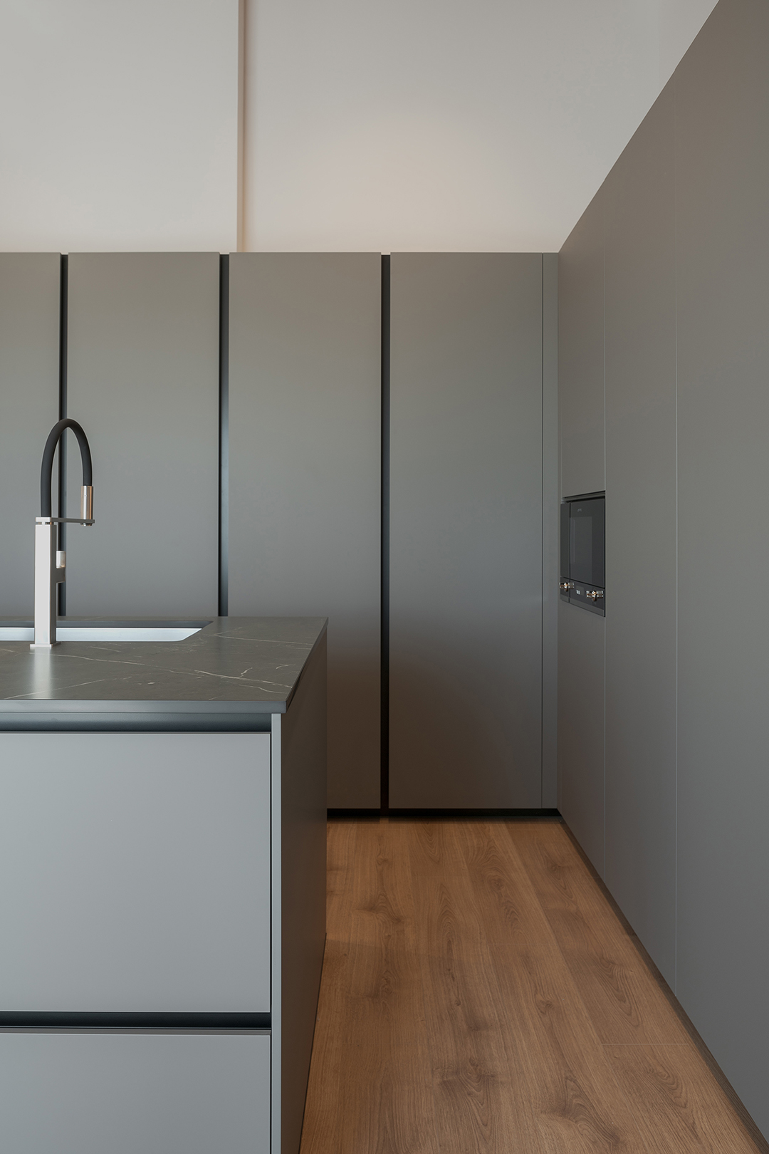 Cocina gris con isla y armarios en columna diseñada por Santos.