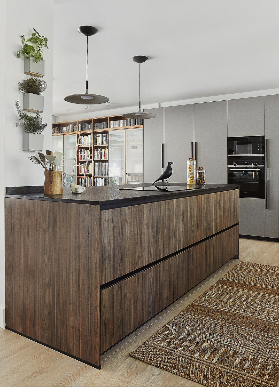 Cocina gris con isla y distribución en L diseñada por Santos.