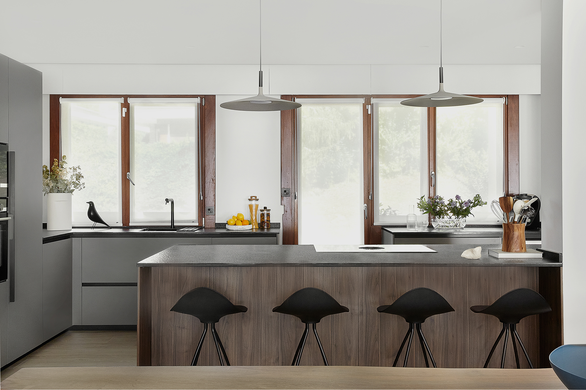 Cocina gris con isla y fregadero bajo la ventana diseñada por Santos.