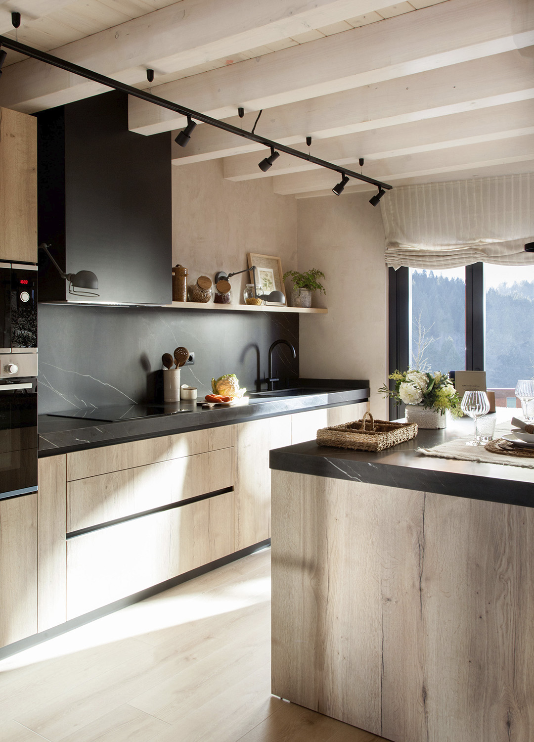 Cocina negra y de madera con isla y cerramiento de cristal de Santos.