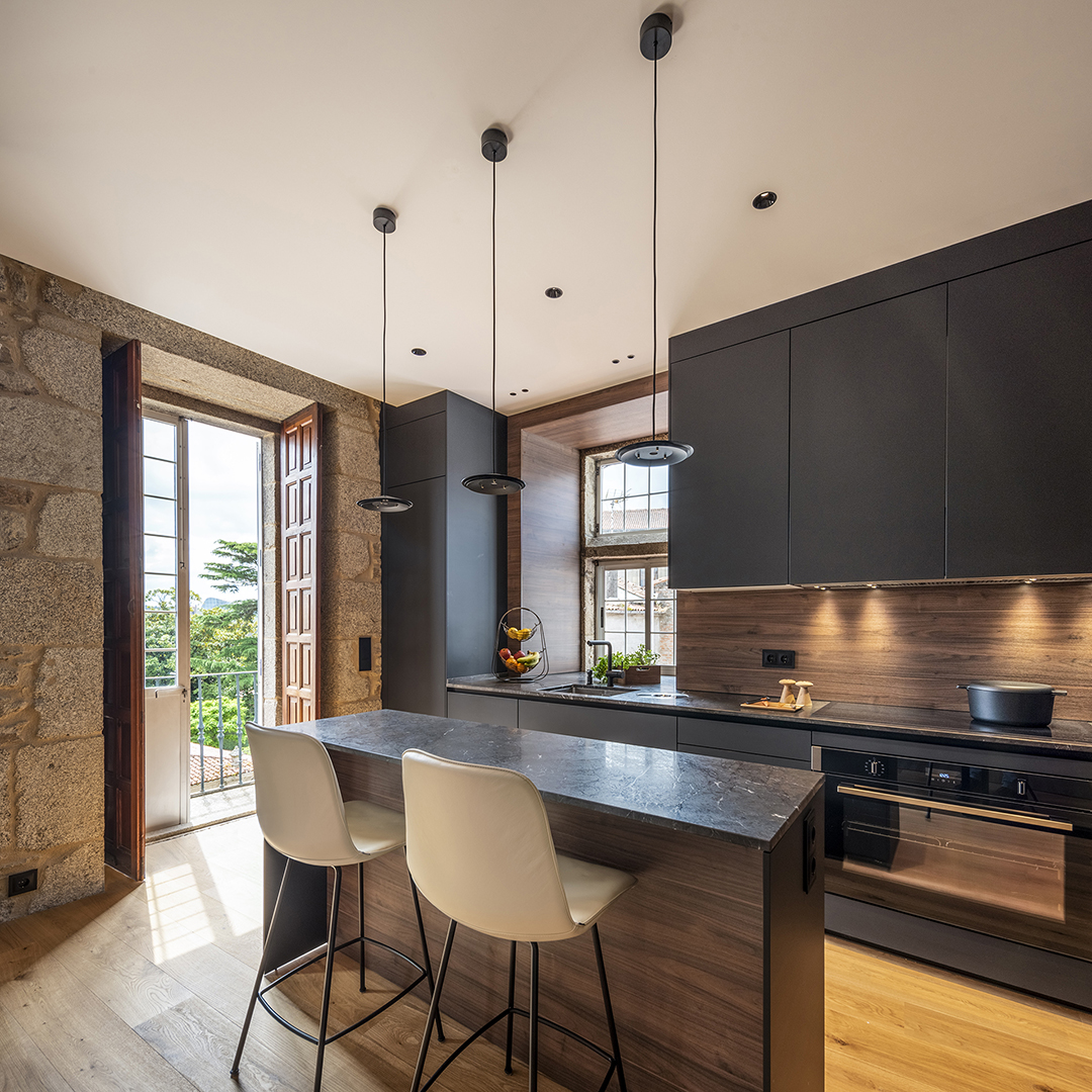 Cocina Negro Seda de Santos con isla y cerramiento de cristal.