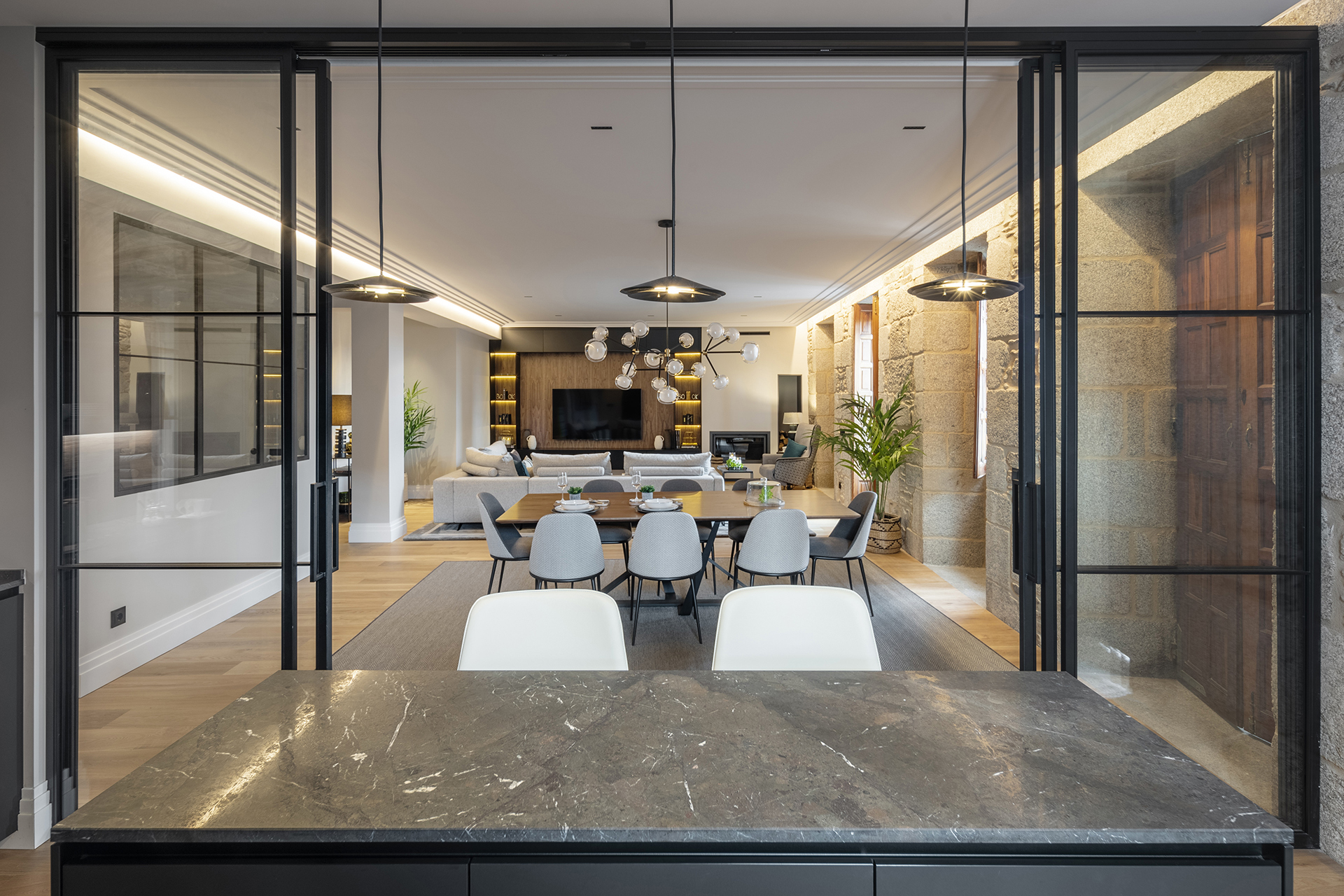 Isla de cocina con cajones en una cocina con cerramiento de cristal abierta al salón.