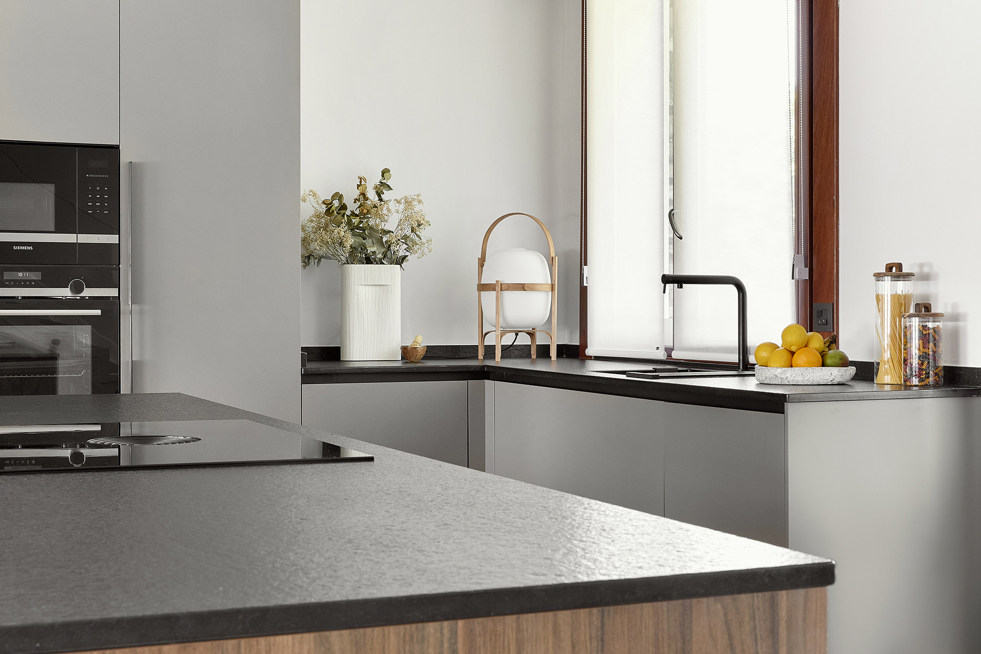 Isla de cocina en gris y madera con fregadero junto a la ventana.