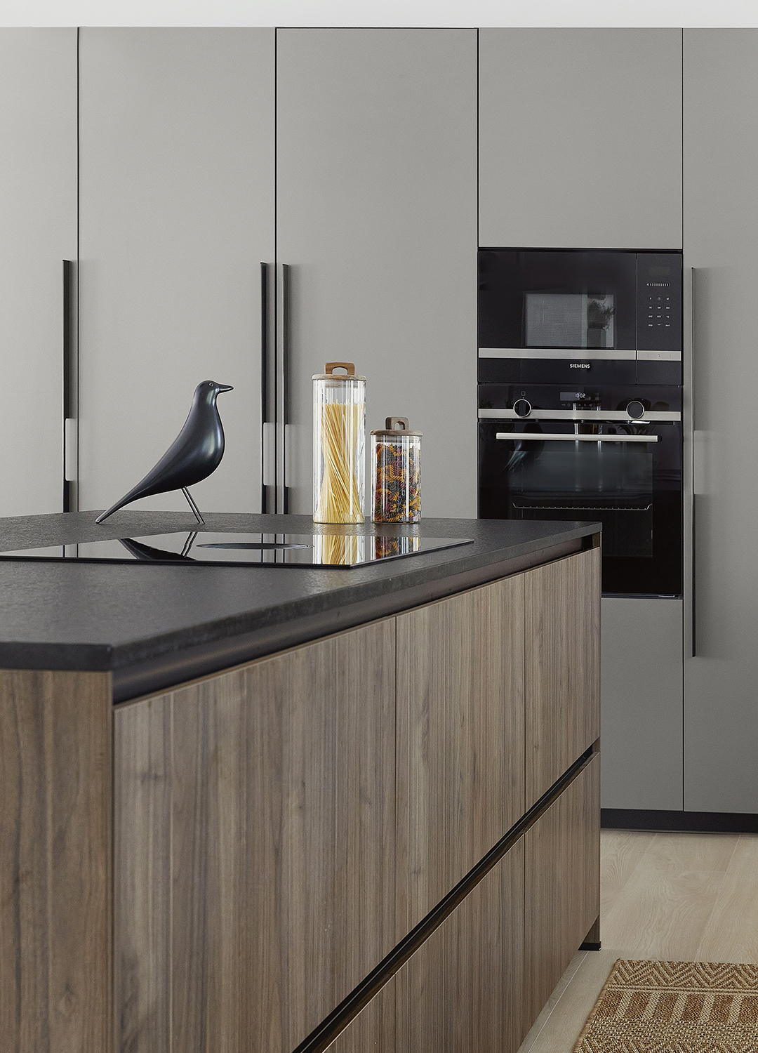 Isla de cocina con acabados en madera y electrodomésticos en columna diseñada por Santos.